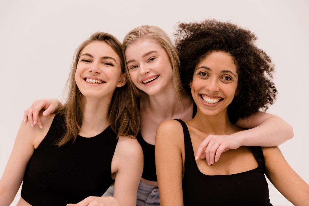 Three girls with different hair types hugging and smiling