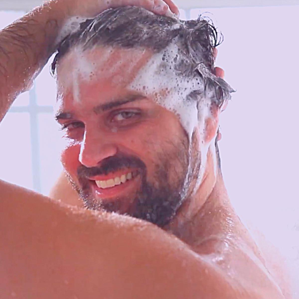 Man washing hair with Tangie citrus shampoo bar in shower